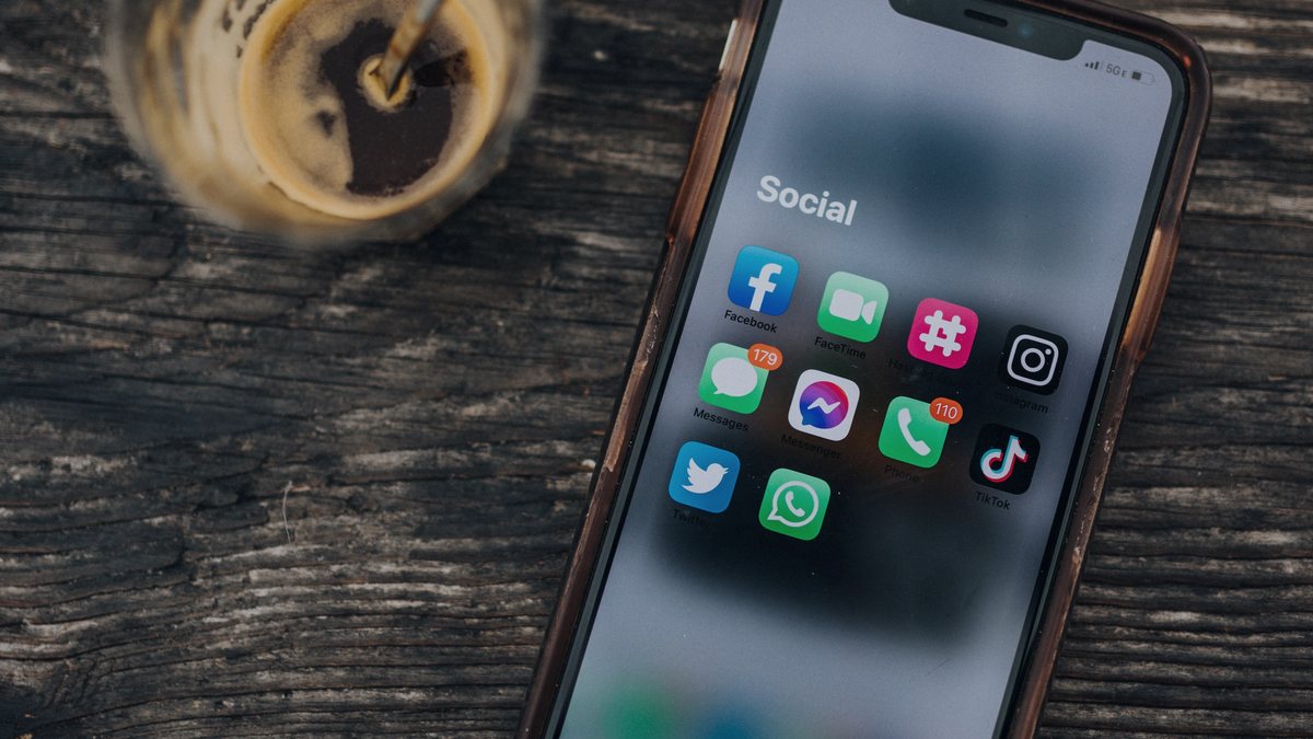 Celular con aplicaciones de redes sociales sobre una mesa de madera